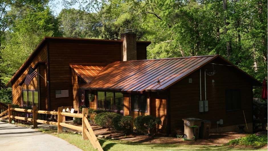 A rustic house with a brown metal roof and trees