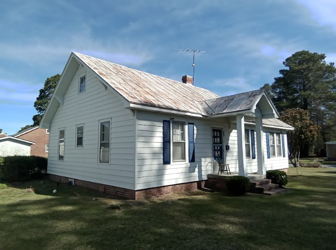 A small white house with metal roofing installation.