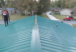 Roofers on a green metal roof