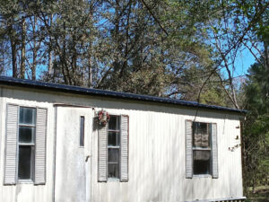 Closer photo of glossy black metal roofing on a white mobile home in South Carolina.